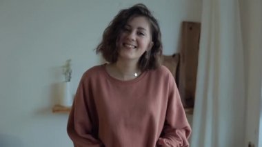 Genç ve güzel bir kız, elinde havuçlarla mutfaktaki dairesinde gülümsüyor.