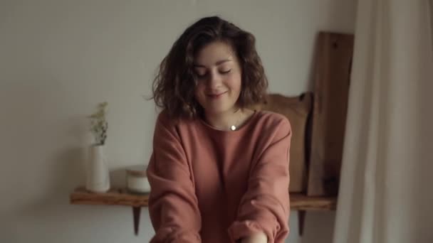 Молодая красивая девушка держит в руках морковь и улыбается в своей квартире на кухне — стоковое видео