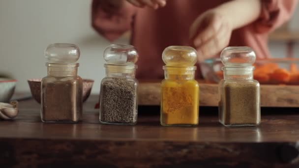 A young girl takes a spoon of spices from cans standing on a table in the kitchen. Close-up — Stock Video