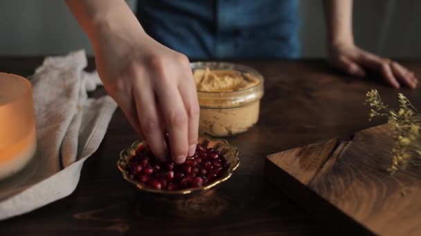 Genç bir kız mutfağında geleneksel bir humus pişirdi ve servis için süsledi. Yakın plan. — Stok video