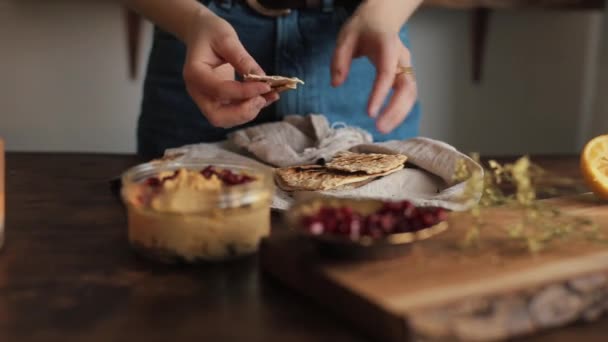 Genç bir kız mutfağında ev yapımı geleneksel humus pişirmiş ve pide parçalarına sürmüş. Yakın plan. — Stok video