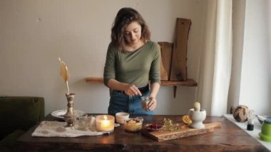 Genç ve güzel bir kız humus hazırlamak için miksere baharat ekler. Köpeği masada oturup onu izlerken.