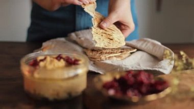 Genç bir kız mutfağında ev yapımı geleneksel humus pişirmiş ve pide parçalarına sürmüş. Yakın plan.