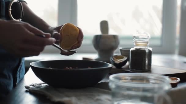 Una chica joven exprime el jugo de un limón y lo agrega al tazón con garbanzos para preparar hummus en casa. Primer plano — Vídeos de Stock