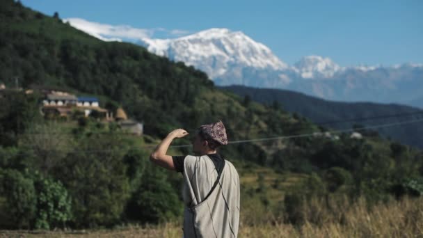 네 팔리의 전통 모자와 옷을 입고 네 팔 산을 바라보는 코카서스 인이다. 풍경 풍경. — 비디오