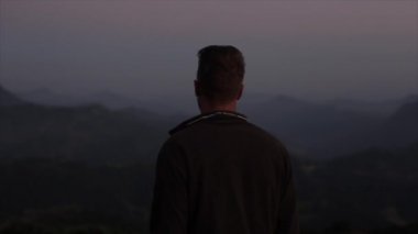 Kafkasyalı bir adamın sisle kaplı dağlara baktığı yakın bir arka plan görüntüsü. İyi akşamlar, sabah..