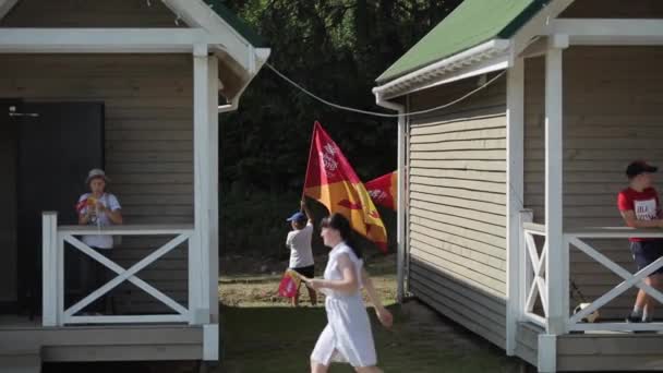 Minsk, Vitryssland - 19 juli 2019: Tonårspojkar med flaggor står i grupp nära hus i bakgrunden av skogen. — Stockvideo