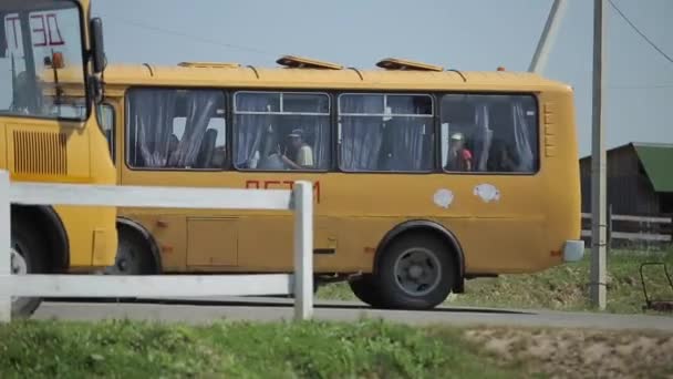 Minsk, Belarus - 19 July 2019: Close-up of a small yellow bus with children holding balloons leaving the countryside. Side view — Stock Video