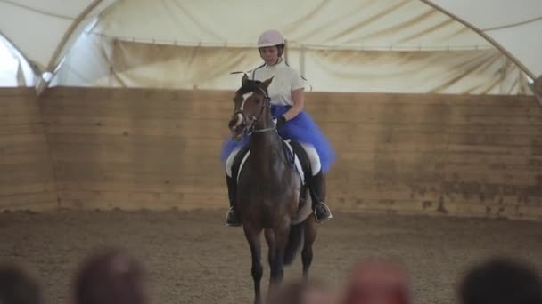 Minsk, Bielorrússia - 19 de julho de 2019: Menina adolescente em um belo vestido azul em seu cavalo na sela a cavalo. Previsão desfocada — Vídeo de Stock