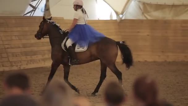 Минск, Беларусь - 19 июля 2019 года: Девушка-подросток в красивом голубом платье на коне в седле на лошади. Размытый передний план — стоковое видео