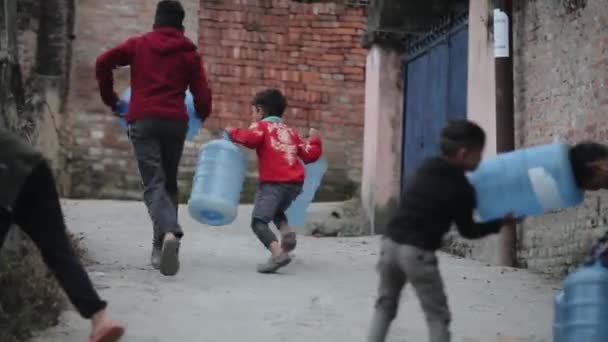 Kathmandu, Nepál - 22. listopadu 2019: Nepálské děti nesoucí na ulici automat na vodu. — Stock video