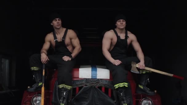 男人做训练。两名强壮的消防员从消防车的车篷上跳下，拿着大锤和斧头走向摄像机 — 图库视频影像