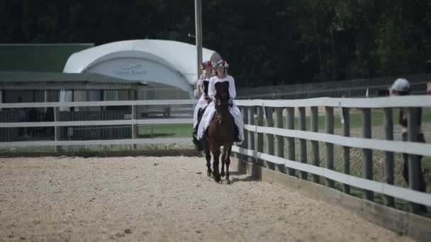 Minsk, Vitryssland - 19 juli 2019: ung flicka i vit medeltida vintageklänning med korsett rida en häst — Stockvideo