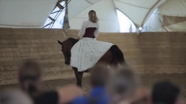 Minsk, Vitryssland - 19 juli 2019: ung flicka i vit medeltida vintageklänning med korsett rida en häst — Stockvideo