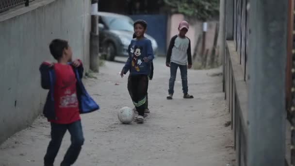 Katmandu, Nepal - 22 listopada 2019: Nepalskie dzieci z Indii lub Azji grające w piłkę nożną, piłka nożna na ulicach. Samochód przejeżdża obok nich i są śmiesznie przyciśnięte do ściany. — Wideo stockowe