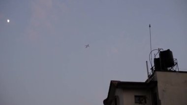 Akşamları gökyüzünde bir uçak. Şehirden görünüm, alçak açı.