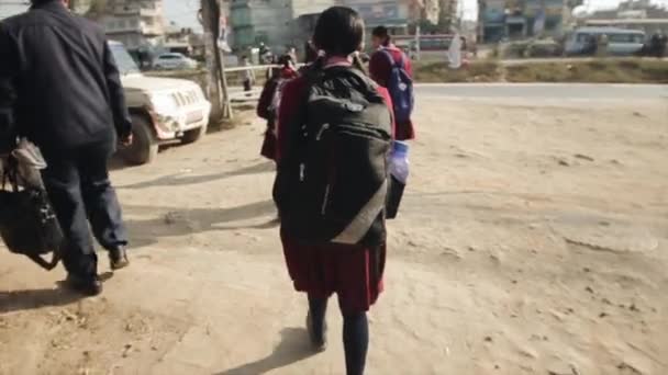 Kathmandu, Nepal - 25. November 2019: Asiatisch-indische Mädchen laufen in Schuluniform und mit Rucksäcken auf den Schultern über die Straße. Rückansicht. Zeitlupe — Stockvideo