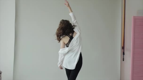 Jong meisje oefent yoga terwijl het doen rekken terwijl het staan met haar rug en leunend zijwaarts met haar hand opgeheven. Langzame beweging — Stockvideo