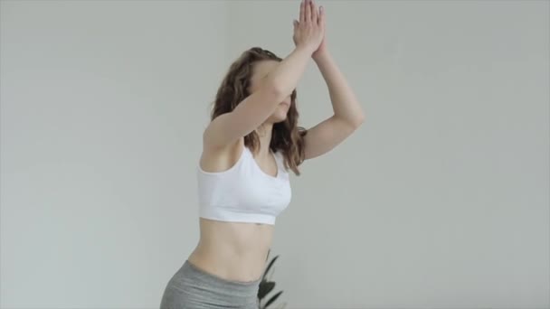 Beautiful young girl practices yoga while doing exercises and meditating at home standing on a mat in sportswear. Close-up — Stock Video