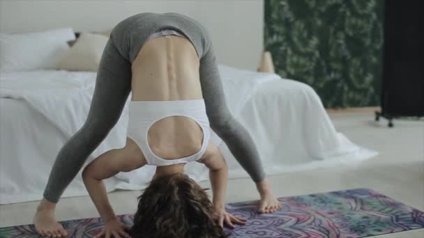 Uma jovem atlética pratica ioga e faz um headstand em casa. Close-up. A câmera se move de baixo para cima. Quarentena covid-19 — Vídeo de Stock