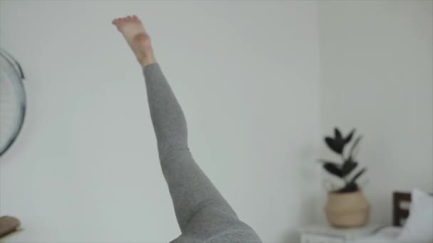 Beautiful young girl is practicing yoga at home. Close-up. The camera follows the girls movements — Stock Video