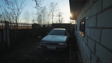 Bobruisk, Belarus - 20 Nisan 2020: Güneşli bir gökyüzüne karşı kırsal bir beyaz tuğla evin avlusunda park edilmiş bir araba. Rus köyü