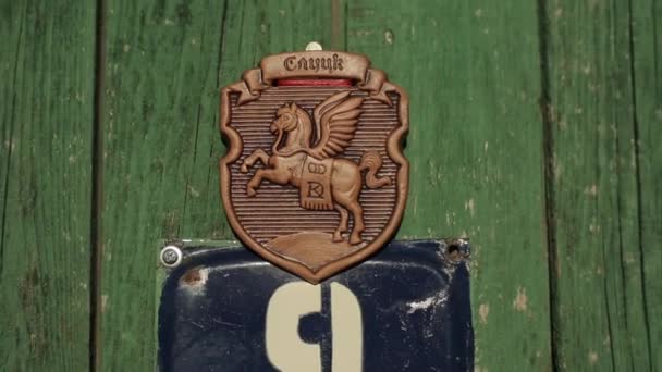 Bobruisk, Belarus - 20 April 2020: Wooden door of a village house with the coat of arms of one of the Slavic cities with a horse. Close-up. Slutsk