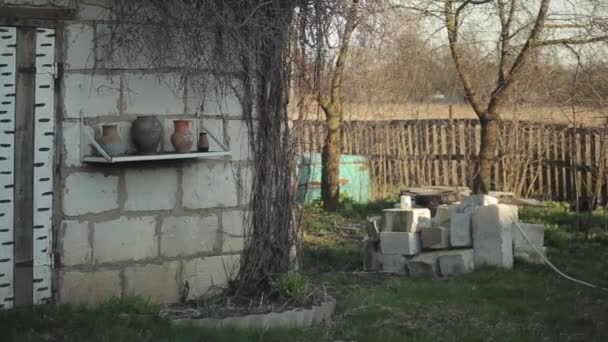 Ein Teil des Dorfhofes mit weißer Ziegelbauweise und einem Regal mit Tonkrügen. Lebensstil russisches Dorf — Stockvideo