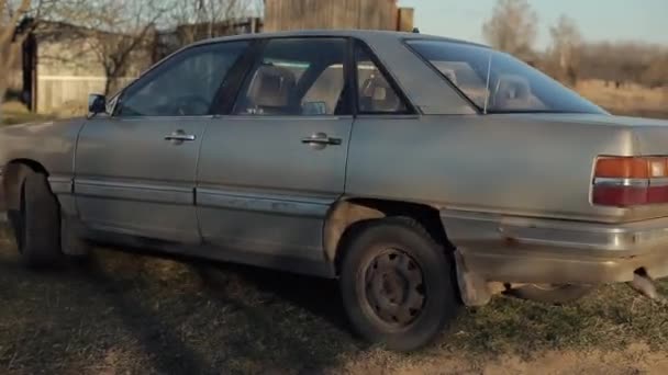 Bobruisk, Bielorrússia - 20 de abril de 2020: Uma jovem de aparência hipster com dreadlocks dirigindo um carro sai em uma estrada da aldeia. Aldeia eslava — Vídeo de Stock