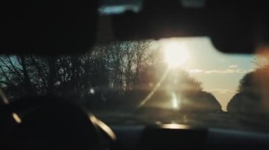 Araba yol boyunca yürüyor ağaçlarla çevrili ve pencere güneşli mavi gökyüzünün güzel bir manzarasını sunuyor