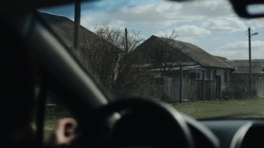 Araba, Rus köyünün yolu boyunca yavaşça ilerliyor. Köy evlerinin ve ahşap çitlerin ön camlarının içine bak. Yavaş çekim