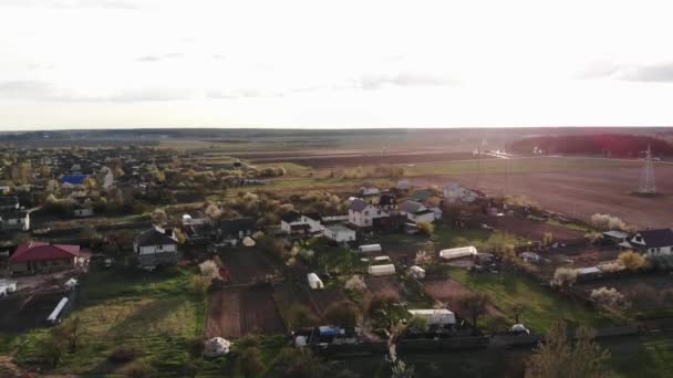 Vista aérea. Hermoso paisaje de tierras de cultivo y casas de pueblo contra el telón de fondo de florecientes jardines de primavera — Vídeos de Stock