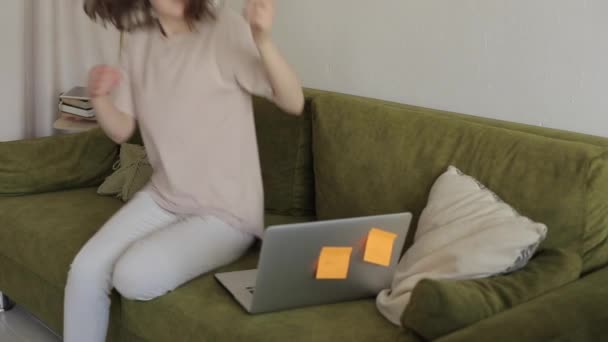 ソファに座っている間にラップトップでオンラインで働いている若いフリーランスの女の子と彼女は彼女の最愛のスパニエルドッグを抱擁するために休憩をしました。閉鎖 — ストック動画