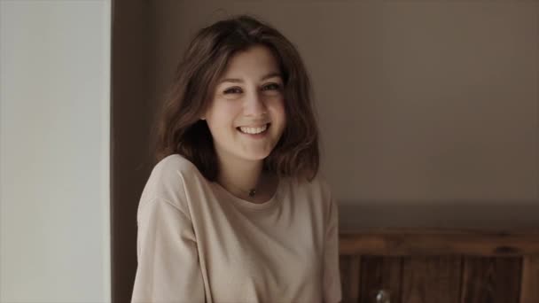 Joven hermosa niña sonriente sostiene pétalos de flores en sus palmas y luego los sopla directamente a la cámara. Primer plano. Movimiento lento — Vídeos de Stock