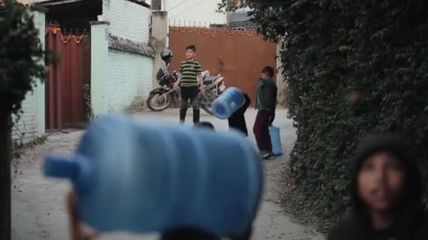 Kathmandu, Nepal - 27 novembre 2019: Un villaggio nepalese. Bambini che portano bottiglie vuote dell'erogatore d'acqua. Nepal, cortile . — Video Stock