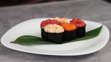 Japon suşi oval gunkan-maki farklı malzemelerle büyük bir tabakta nori yapraklarına sarılmış. Makro çekim