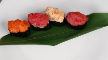 Genç bir kız, oval suşi şeklindeki çeşitli dolgularla dolu bir Gunkan maki tabağı takıyor. Geleneksel Japon yemekleri. Makro atış. Yukarıdan görüntüle