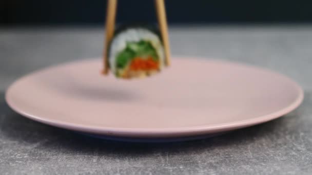 Rolos japoneses com um recheio brilhante de peixe vermelho e verduras verdes em uma chapa. Comida asiática tradicional. Macro shot. 4K — Vídeo de Stock
