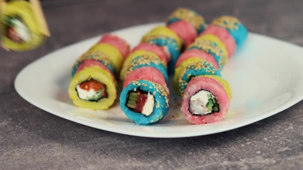 Regenbogen-Sushi. Reisrollen in verschiedenen Farben gefüllt mit rotem Fisch und frischem Gemüse. Asiatisches Essen. Makroaufnahme — Stockvideo