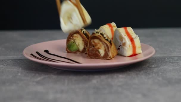 Japonské jasně sladké sushi rolky s různými druhy ovoce a tvarohové smetany zabalené v palačinkách a máčené sirupem a čokoládou. Makro snímek — Stock video