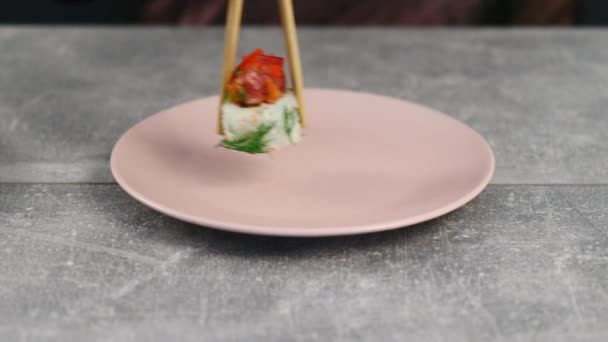 Sushi broodjes rijst en verse zeevruchten met dille worden verspreid op een bord met eetstokjes. Traditioneel Japans eten. Macro neergeschoten. — Stockvideo
