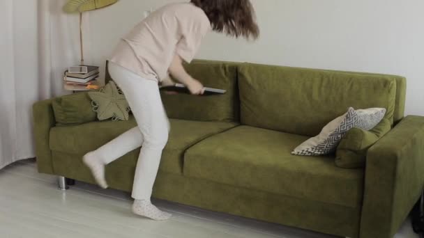 Seorang gadis pekerja lepas bekerja pada laptop tergeletak di sofa dan lelah menutupnya dan meninggalkan ruangan. Close-up — Stok Video