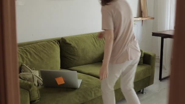 Die junge schöne Freiberuflerin arbeitet zu Hause und unterhält sich lebhaft online auf einem Laptop, während sie auf einem Sofa in ihrem Zimmer sitzt. Nahaufnahme — Stockvideo