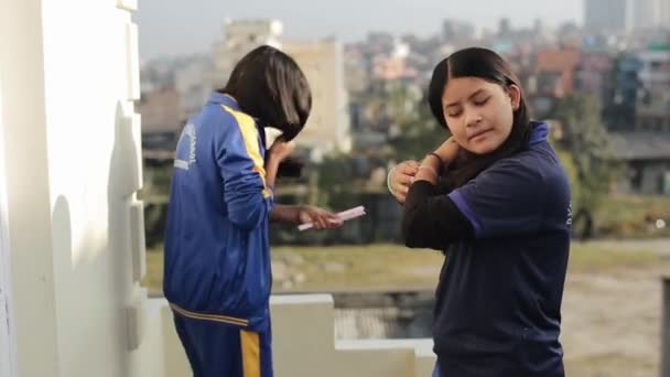 Katmandu, Nepal - 27 Kasım 2019: İki çekici Hintli Nepalli genç kız bir yetimhanenin balkonunda saçlarını tarayıp konuşuyorlar. Yakın plan. — Stok video