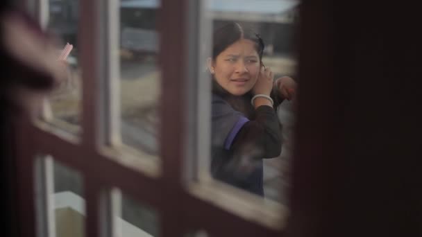 Katmandou, Népal - 27 novembre 2019 : Des adolescentes népalaises indiennes se rassemblent à l'école et tressent leurs cheveux debout sur le balcon. Tirer par la fenêtre. Un gros plan. Fond avant flou — Video