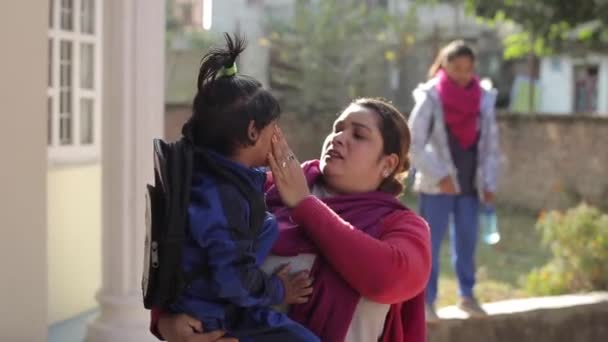 Kathmandu, Nepál - 27. listopadu 2019: Atraktivní indická nepálská žena stojí s malou holčičkou v náručí na dvoře domu a vedle ostatních dětí. Detailní záběr — Stock video