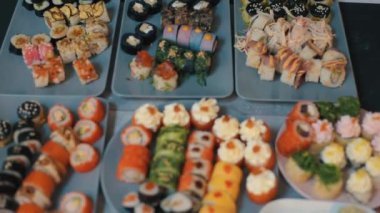Farklı türde parlak taze suşi ruloları ve masada farklı malzemeler. Geleneksel Japon mutfağı. Makro atış. Kamera odağı değiştirir.