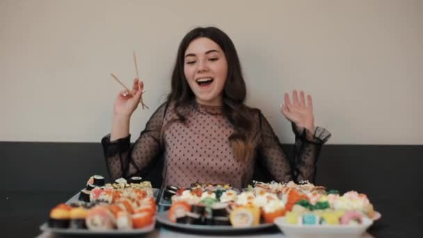 Spännande av mängden sushi på bordet den unga flickan är förlorad och slutligen väljer en rulle. Wow effekt. Kameran ändrar fokus. Närbild — Stockvideo