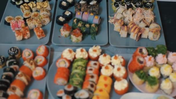 Élénk, friss sushi tekercsek, különböző feltétekkel az asztalon. Hagyományos japán konyha. Makró lövés. A kameraváltás fókusza — Stock videók