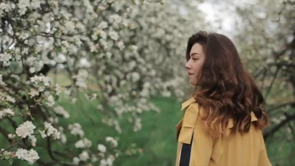 Schöne zarte junge Mädchen spaziert durch den frühlingsblühenden Garten und blickt zurück in die Kamera. Nahaufnahme. Zeitlupe — Stockvideo